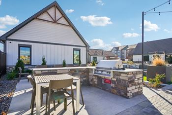 A patio with a grill and a table and chairs